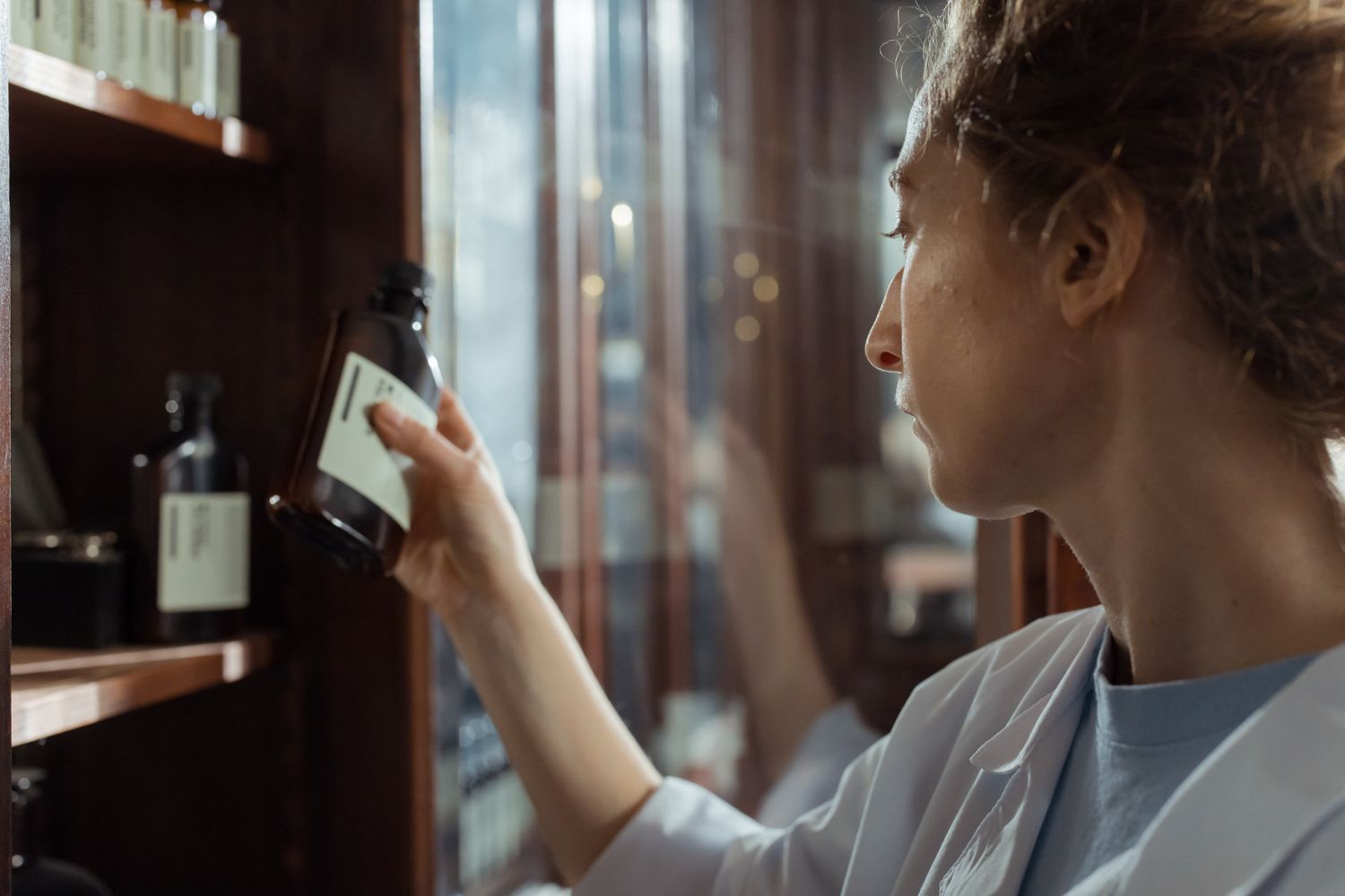 Pharmacist selecting a product from pharmacy shelves — illustrative stock photograph